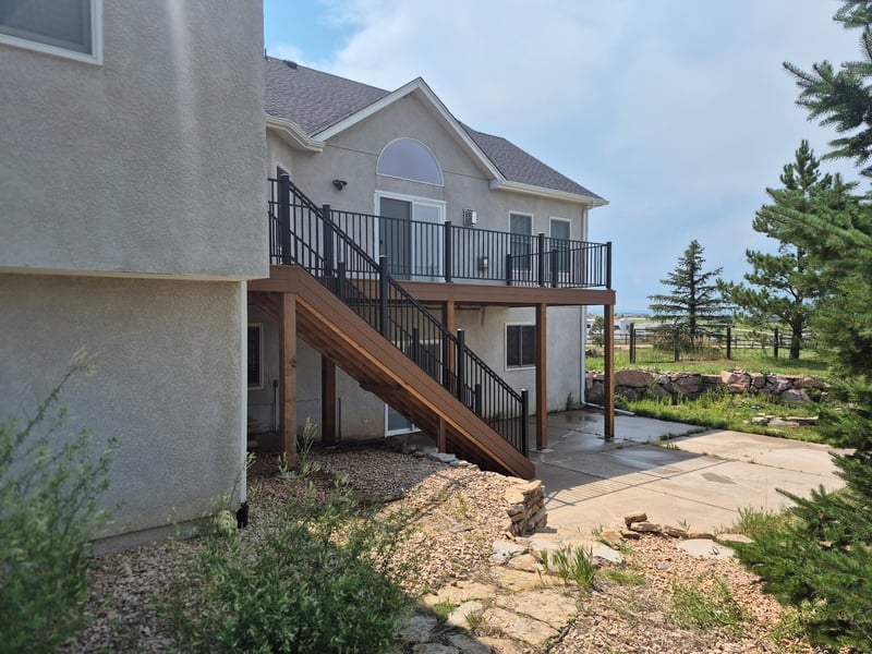 Composite deck with black metal railings overlooking a mountain backyard