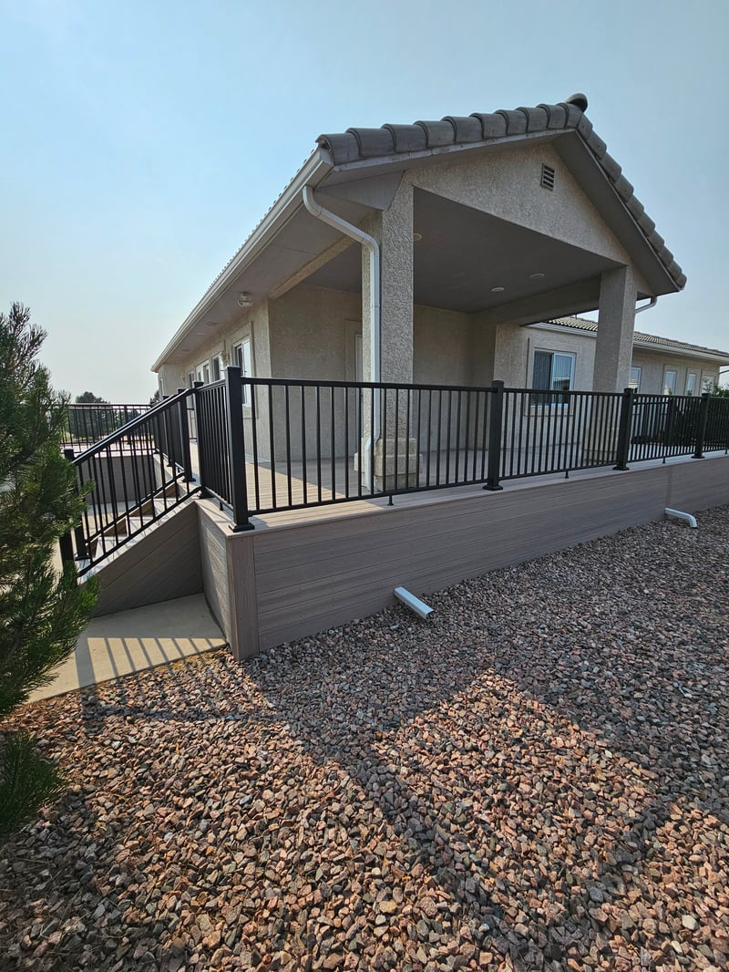 Composite deck with black metal railings overlooking a mountain backyard