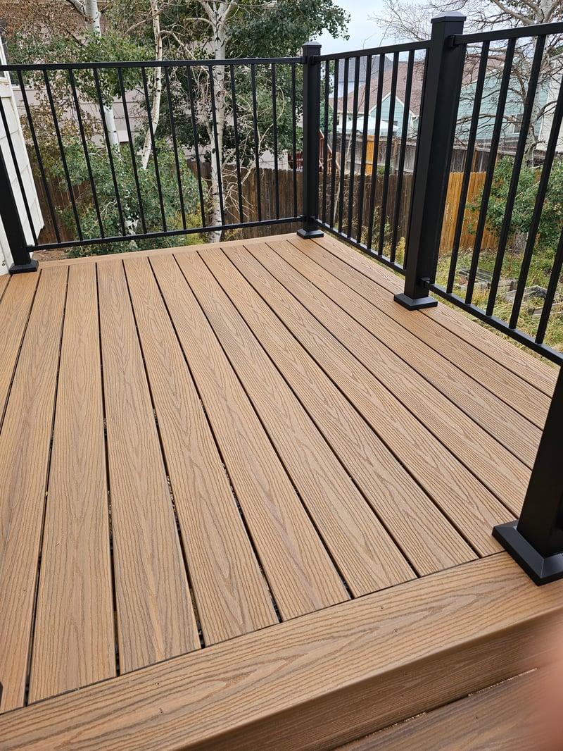 Composite deck with black metal railings overlooking a mountain backyard