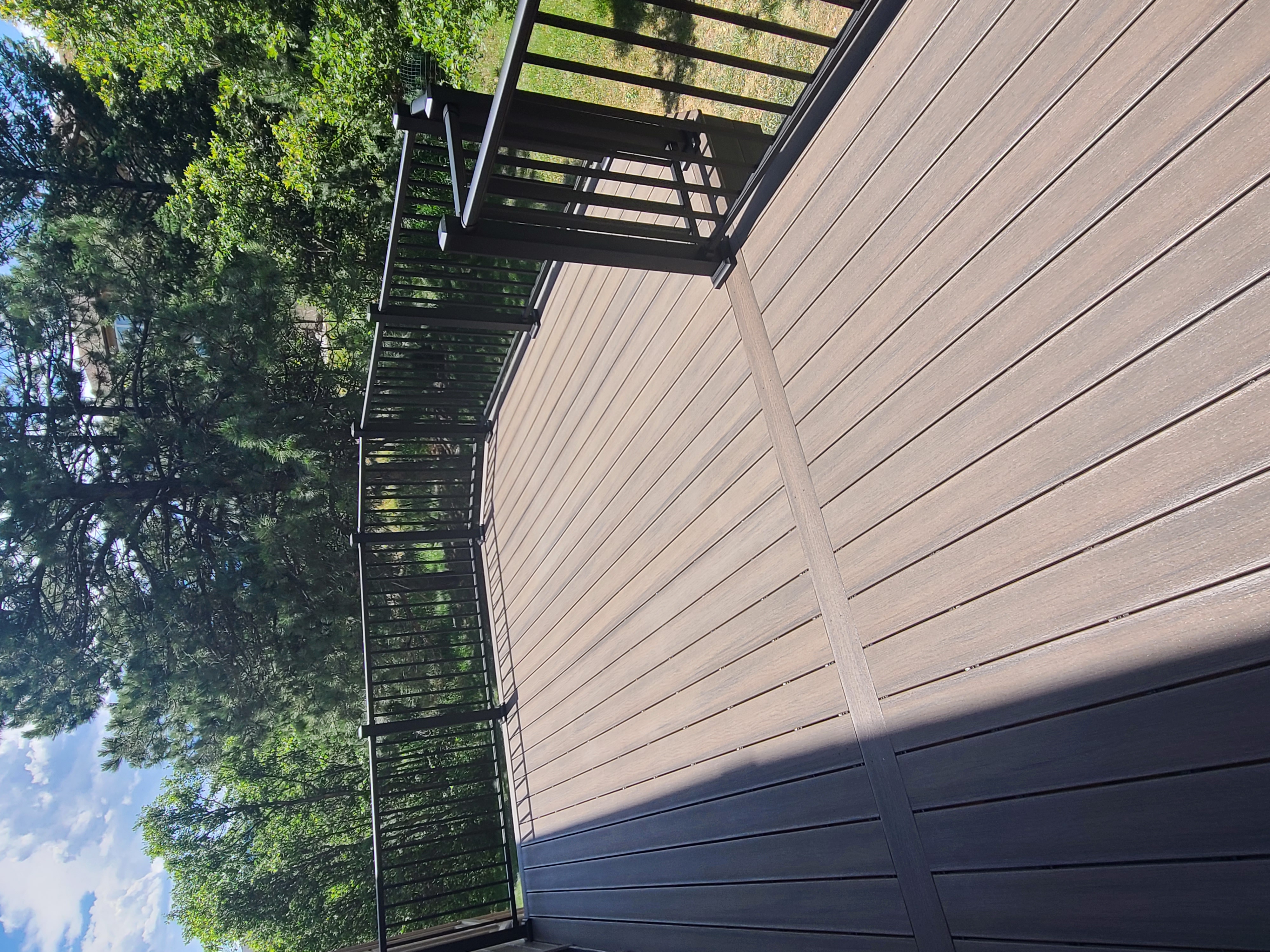 Composite deck with black metal railings overlooking a mountain backyard