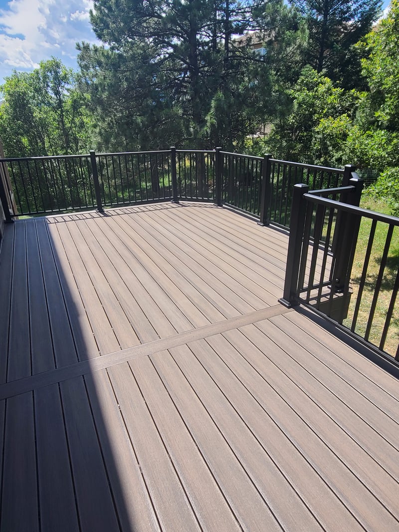Composite deck with black metal railings overlooking a mountain backyard