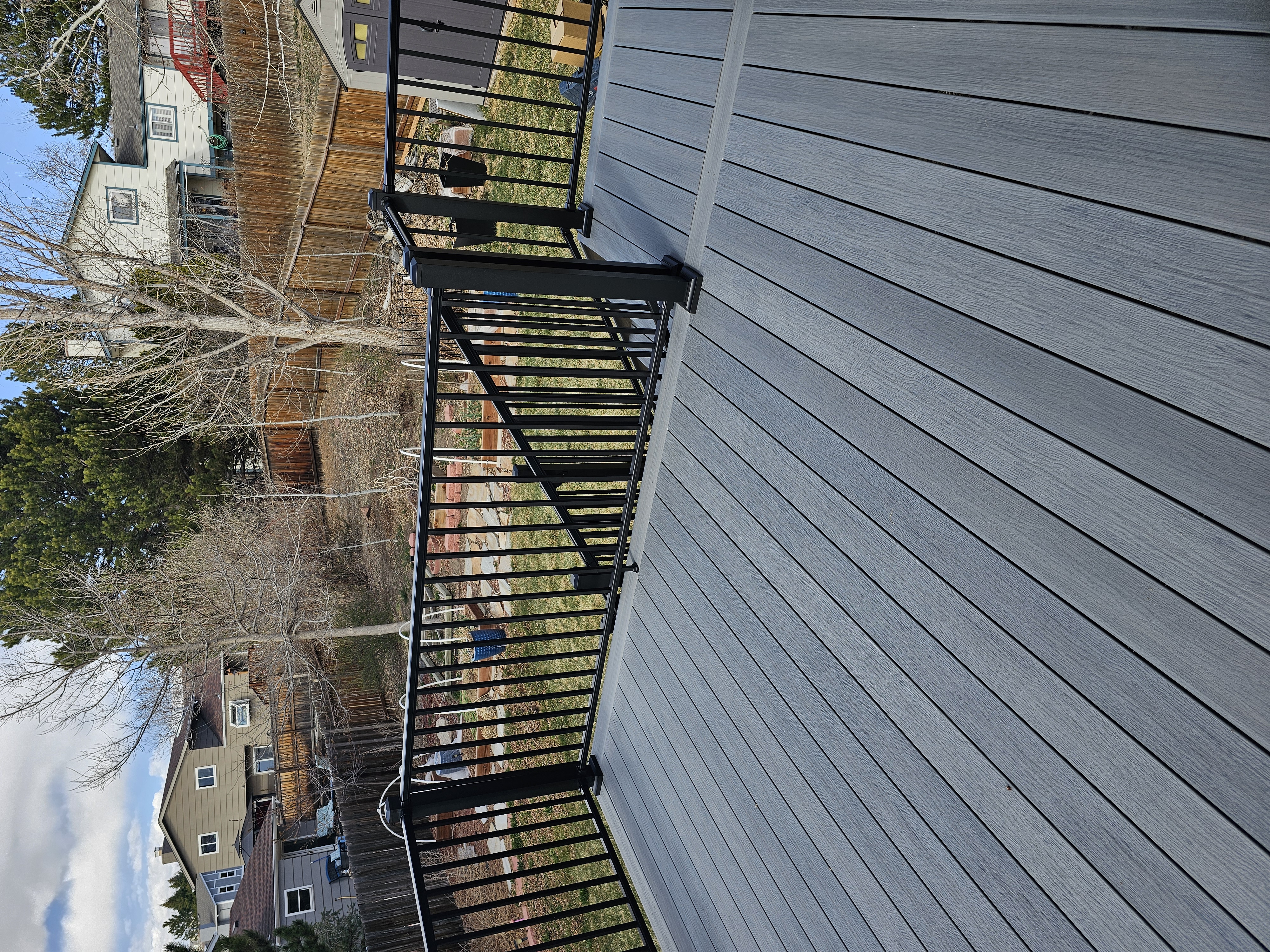 Composite deck with black metal railings overlooking a mountain backyard