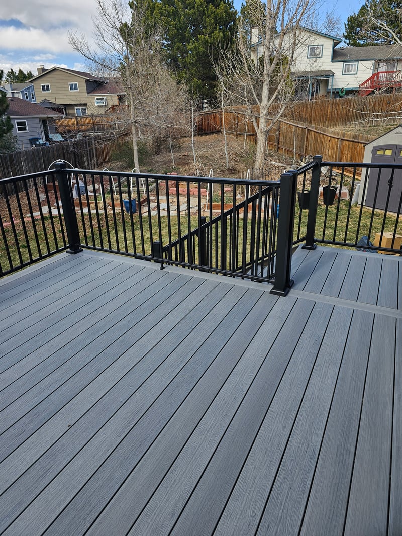 Composite deck with black metal railings overlooking a mountain backyard
