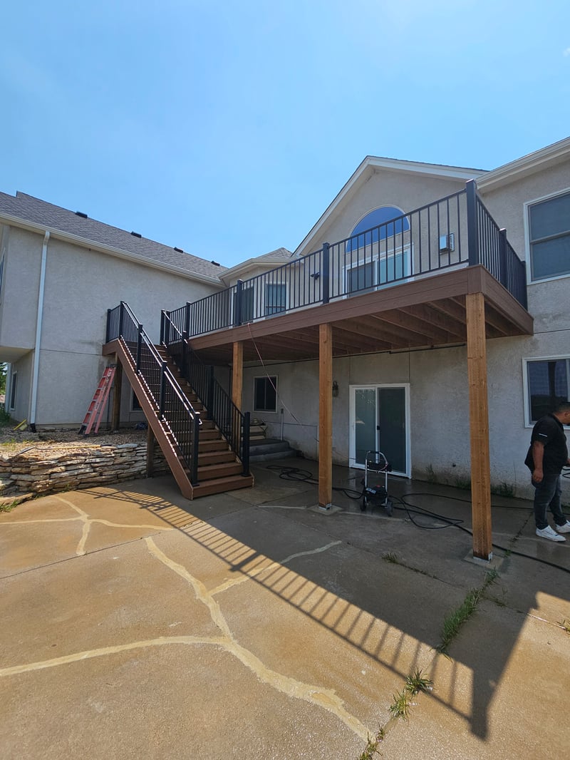 Composite deck with black metal railings overlooking a mountain backyard