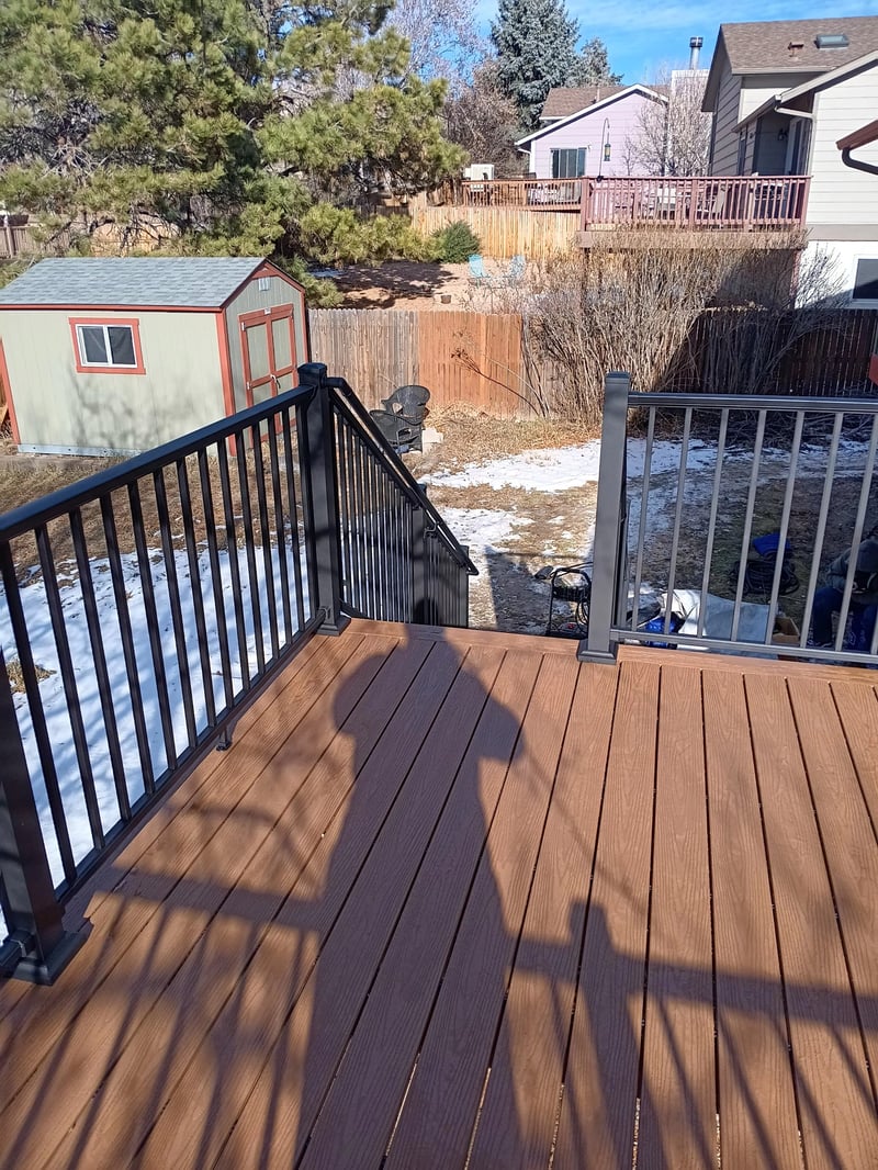 Composite deck with black metal railings overlooking a mountain backyard