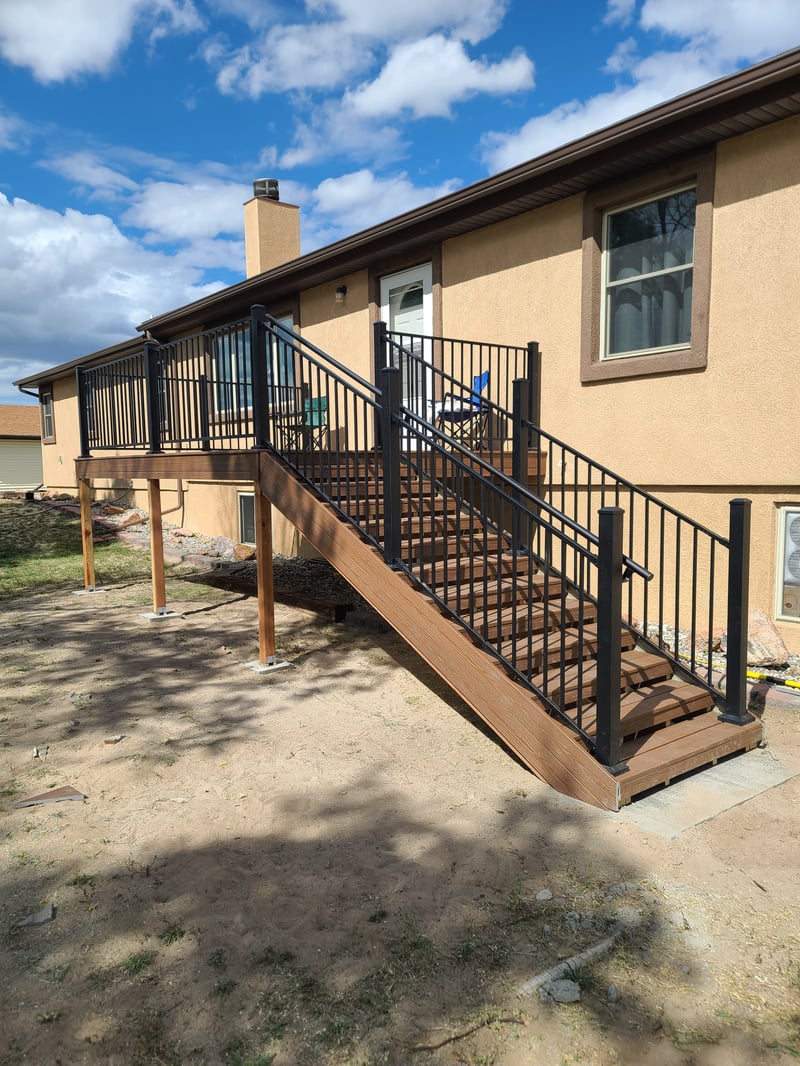 Composite deck with black metal railings overlooking a mountain backyard