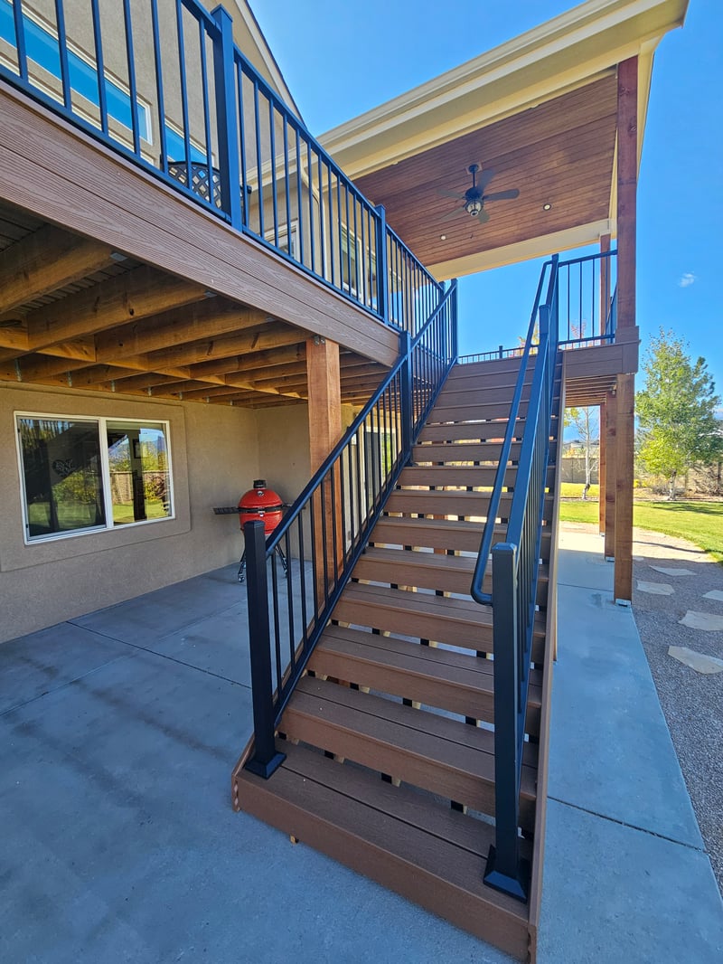 Composite deck with black metal railings overlooking a mountain backyard