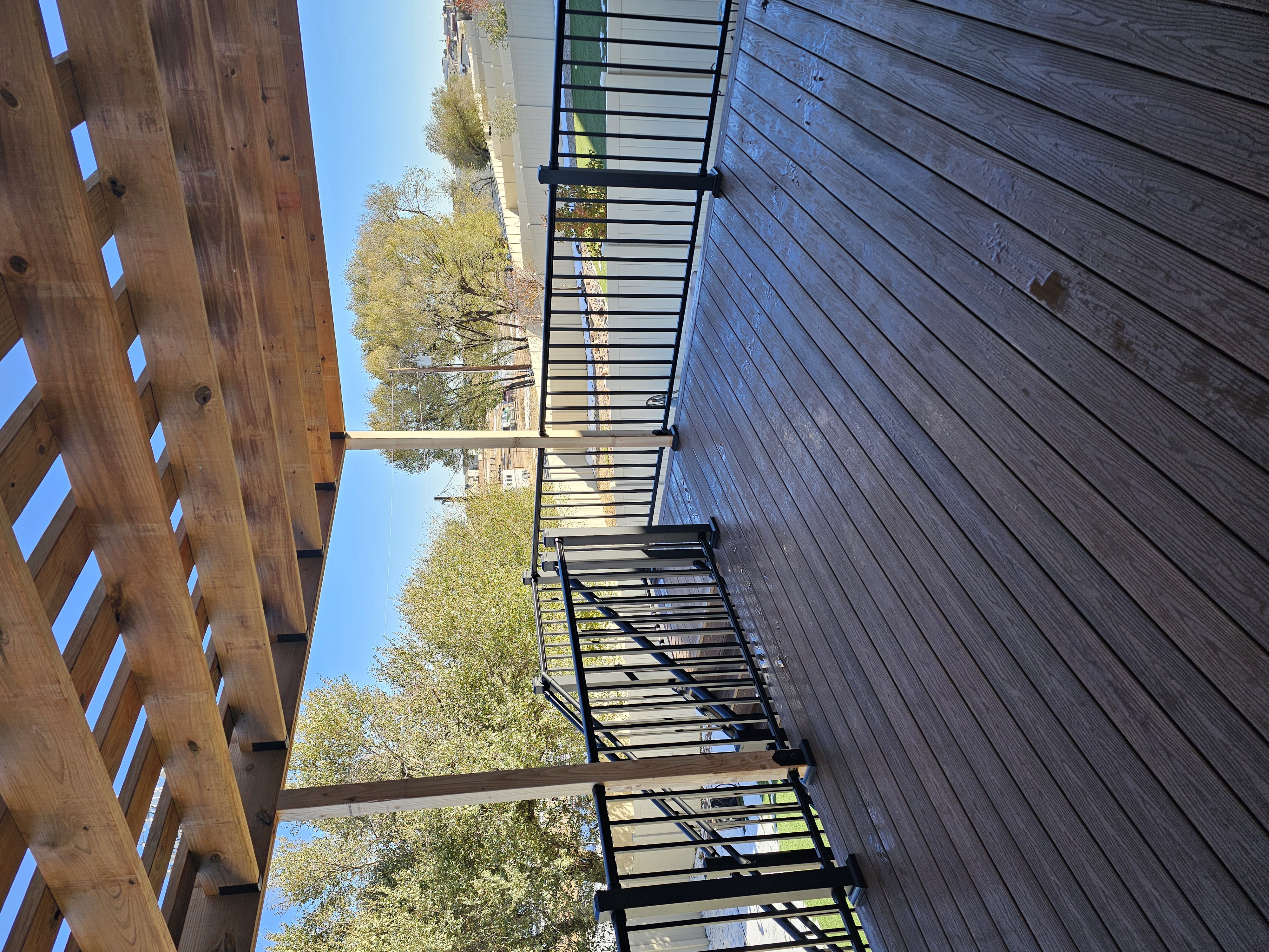 Composite deck with black metal railings overlooking a mountain backyard