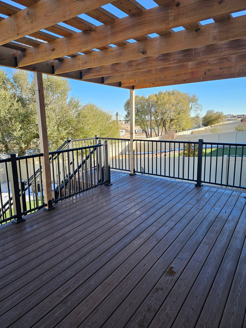Composite deck with black metal railings overlooking a mountain backyard